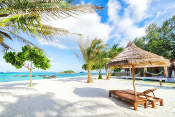 Empty sunny Koh Lipe Beach with tall palms and beach bungalows