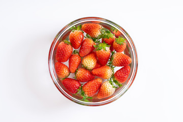 Fresh strawberries in water bowl on white background