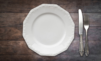 empty plate, fork and knife on wood table, flat lay -