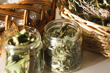 Jars and wicker baskets with medicinal magic herbs, illuminated by the sun