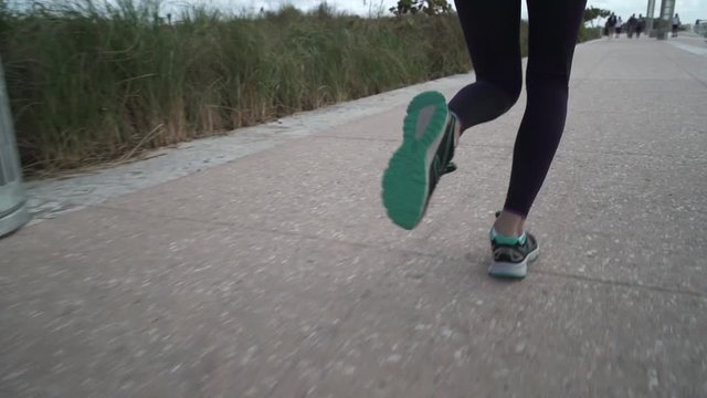 Slow motion close up of fit woman's legs running on concrete path