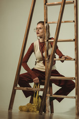 beautiful stylish girl with lemons in string bag posing near ladder