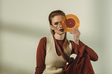attractive young woman holding vintage vinyl record on beige
