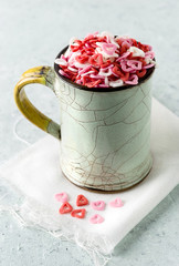 Sugar hearts in a cup on delicate background