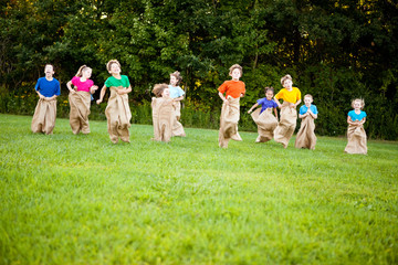 Happy Kids Having Potato Sack Race Outside