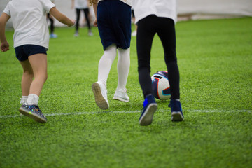 Fototapeta na wymiar Children playing football indoors. Kids running on the field