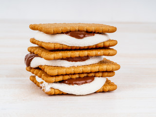 Smores, marshmallow sandwiches - traditional American sweet chocolate cookies on white wooden table, side view