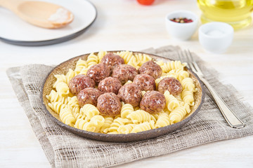 Swedish meatballs with fusilli paste on white wooden table, side view