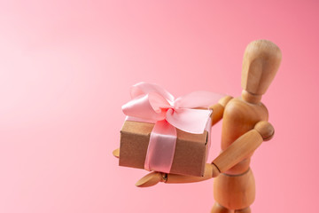 Wooden toy model giving gifts on pink background. Holiday card for Valentine's day and women's day