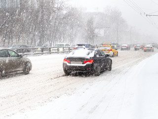cars drive at slippery street in snow blizzard