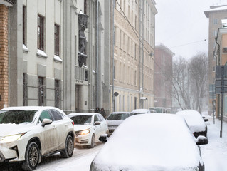 car traffic at narrow street city in snowfall