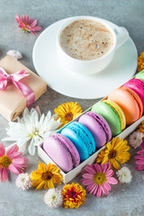 Photo of cake macarons, gift box, tea, coffee, cappuccino and flowers. Sweet romantic food macaroon concept. Morning breakfast and presents. Valentine's day concept.