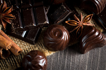 Assortment of dark, white and milk chocolate stack, chips. Chocolate and coffee beans on rustic wooden sacking background. Spices, cinnamon. Selective macro focus. Chocolates background. Sweets