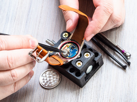watchmaker installs battery in quartz wristwatch