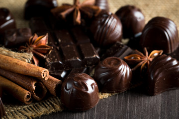 Assortment of dark, white and milk chocolate stack, chips. Chocolate and coffee beans on rustic wooden sacking background. Spices, cinnamon. Selective macro focus. Chocolates background. Sweets