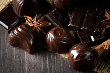 Assortment of dark, white and milk chocolate stack, chips. Chocolate and coffee beans on rustic wooden sacking background. Spices, cinnamon. Selective macro focus. Chocolates background. Sweets