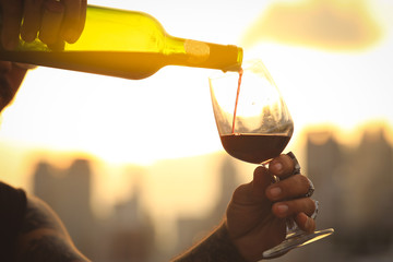 Glass and bottle of red wine in selective focus on glass of wine. pouring red wine at sunset