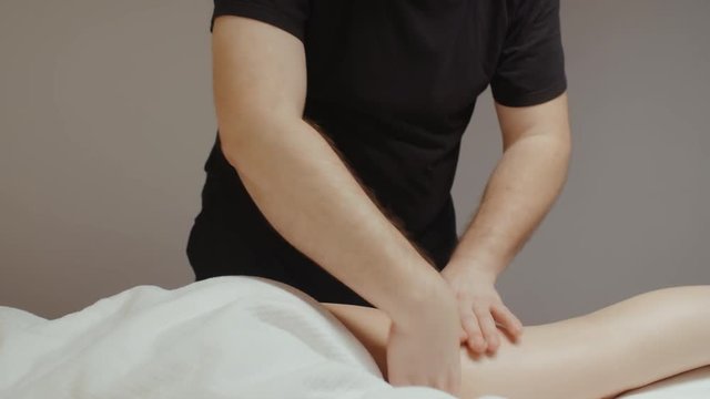 Male masseur doing leg hip anti cellulite massage. Slim young woman receiving health body rejuvenating procedure in spa salon