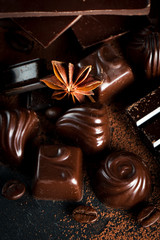 Assortment of dark, white and milk chocolate stack, chips. Chocolate and coffee beans on rustic wooden sacking background. Spices, cinnamon. Selective macro focus. Chocolates background. Sweets