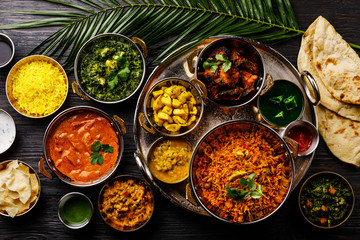Indian food Curry butter chicken, Palak Paneer, Chiken Tikka, Biryani, Vegetable Curry, Papad, Dal, Palak Sabji, Jira Alu, Rice with Saffron on dark background - obrazy, fototapety, plakaty