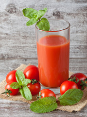 Close-up of a glass of tomato juice with vegetables on wooden sacking background. Vitamins and minerals. Healthy drink concept.