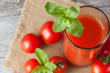 Close-up of a glass of tomato juice with vegetables on wooden sacking background. Vitamins and minerals. Healthy drink concept.