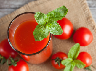 Close-up of a glass of tomato juice with vegetables on wooden sacking background. Vitamins and minerals. Healthy drink concept.