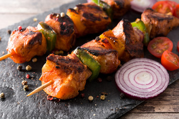 Chicken shish kebab with vegetables on black stone