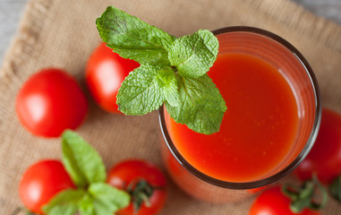 Close-up of a glass of tomato juice with vegetables on wooden sacking background. Vitamins and minerals. Healthy drink concept.