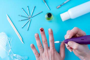 Female manicurist doing a professional manicure hardware using milling cutter on the background of the tools