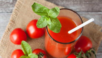 Close-up of a glass of tomato juice with vegetables on wooden sacking background. Vitamins and minerals. Healthy drink concept.
