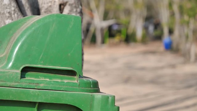 Hand of woman putting empty clear plastic bottle into green garbage bin for recycle concept