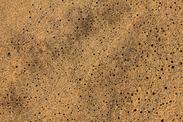 gray yellow sand with black holes close up. natural surface texture
