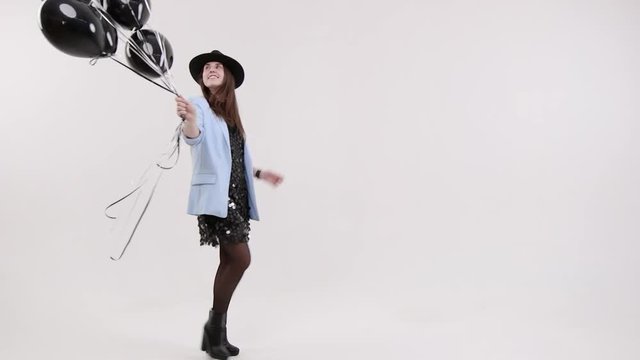 Woman with black balls on a white background in the studio. Jeans clothes.