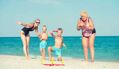 Children together with their mother and grandmother playing a game throwing rings on the beach