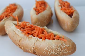 Incredibly delicious and juicy hotdogs with carrots on the white table. 