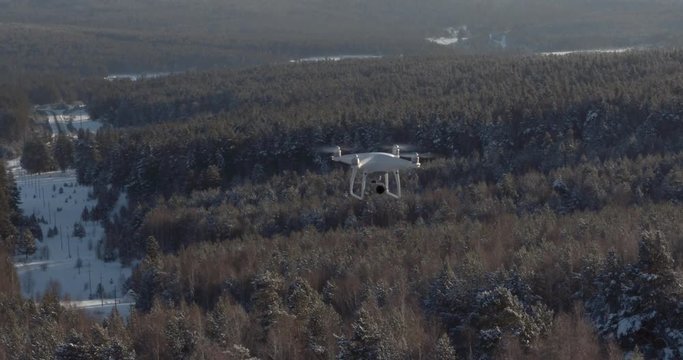Aerial View Drone DJI Phantom 4 Pro in flight from another drone over the forest mountains in winter frozen day. Reconnaissance drone.