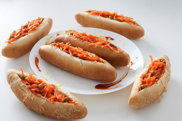 Incredibly delicious and juicy hotdogs with carrots on the white table. 