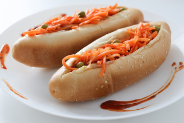 Incredibly delicious and juicy hotdogs with carrots on the white table. 