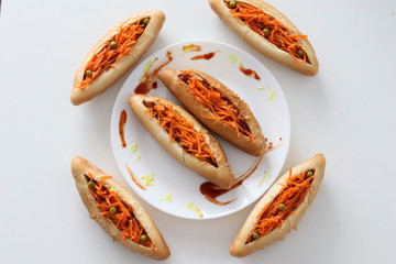 Incredibly delicious and juicy hotdogs with carrots on the white table. 