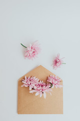 Craft envelope full of flowers. Flat lay on white background