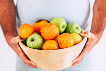 Cup of colored mixed seasonal fresh fruit holded by man with big fat belly - concept of eat healty and do diet - vegetarian and vegan food - vitamin and sport activity needs