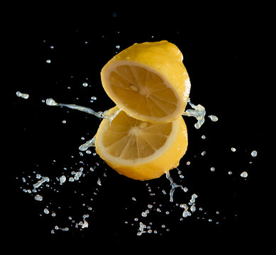 Lemom slice with juice splash isolated on black background