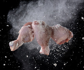 Chicken leg with flour splash or explosion flying in the air on black background,Stop motion