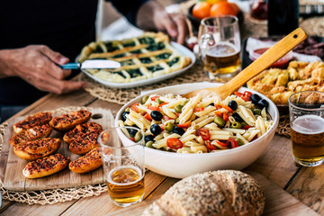 Close up of dish full of italian pasta and mixed food for ñunch or dinner time in friendship for group of people have fun and enjoy to stay together - celebration and event - wooden table and colors