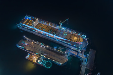 Aerial view container ship in shipyard for repair at night. Can use for shipping or transportation concept.