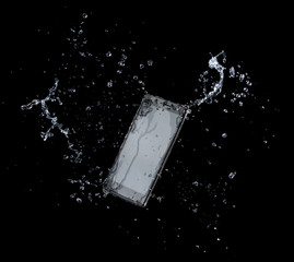 Smartphone with splashing of water or explosion flying in the air isolated on black background