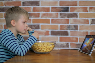 Young boy looking on a digital tablet with popcorn