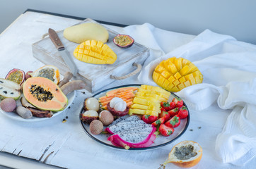 Many kinds of tropical fruits on white table. Mangosteen, lychee, tamarind, cherimoya, granadilla, mango, passion fruit, rambutan, strawberry, papaya.