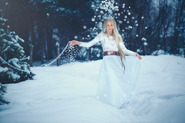 Fototapeta na wymiar Winter Beauty Woman. Beautiful fashion model girl with snow hairstyle and makeup in the winter forest. Festive makeup and manicure. Winter Queen with snow and ice hairstyle
